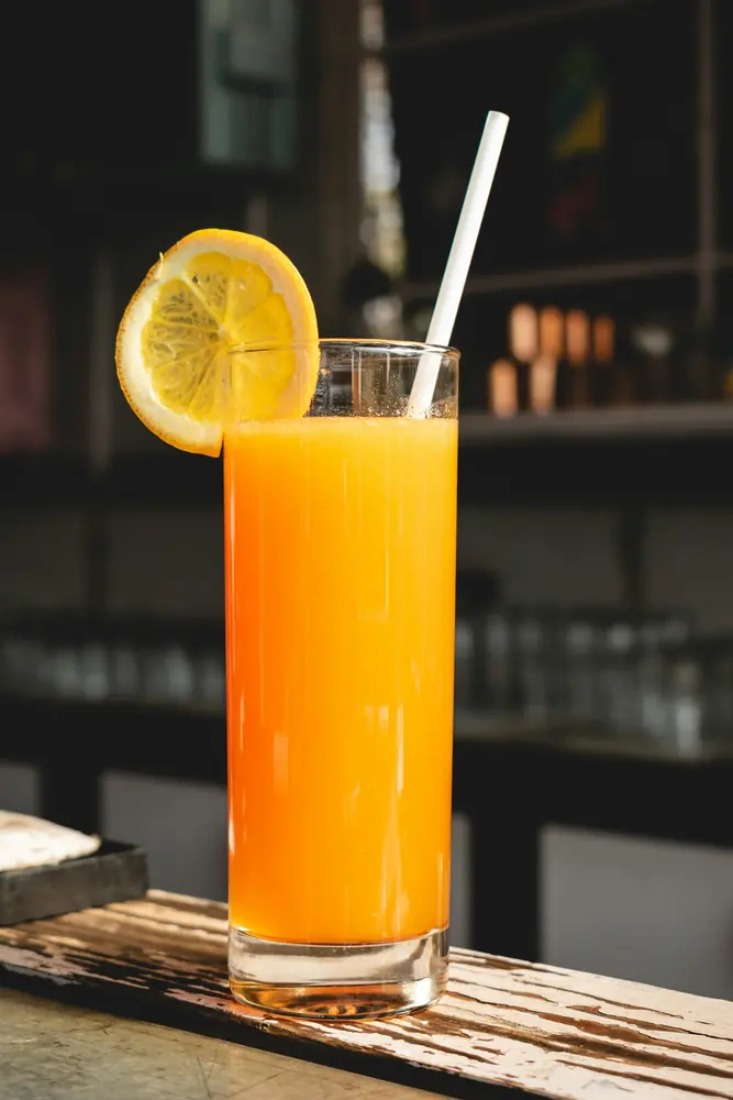 A tall glass of fresh orange juice with a straw